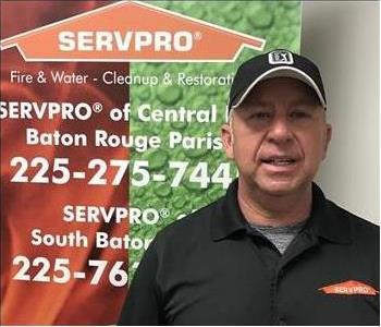 Male employee Jeff Betz, franchise owner, posing in front of a SERVPRO poster.