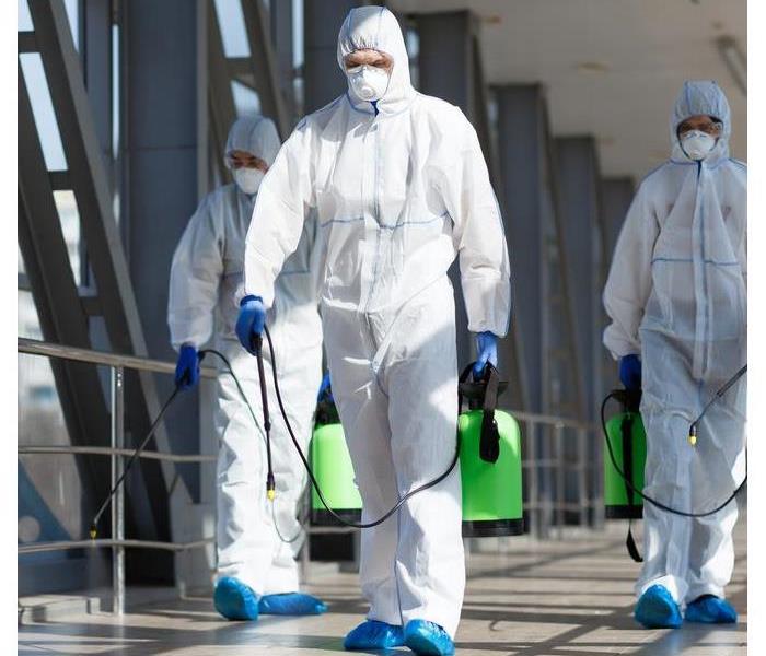 People in virus protective suits and mask disinfecting buildings of coronavirus with the sprayer